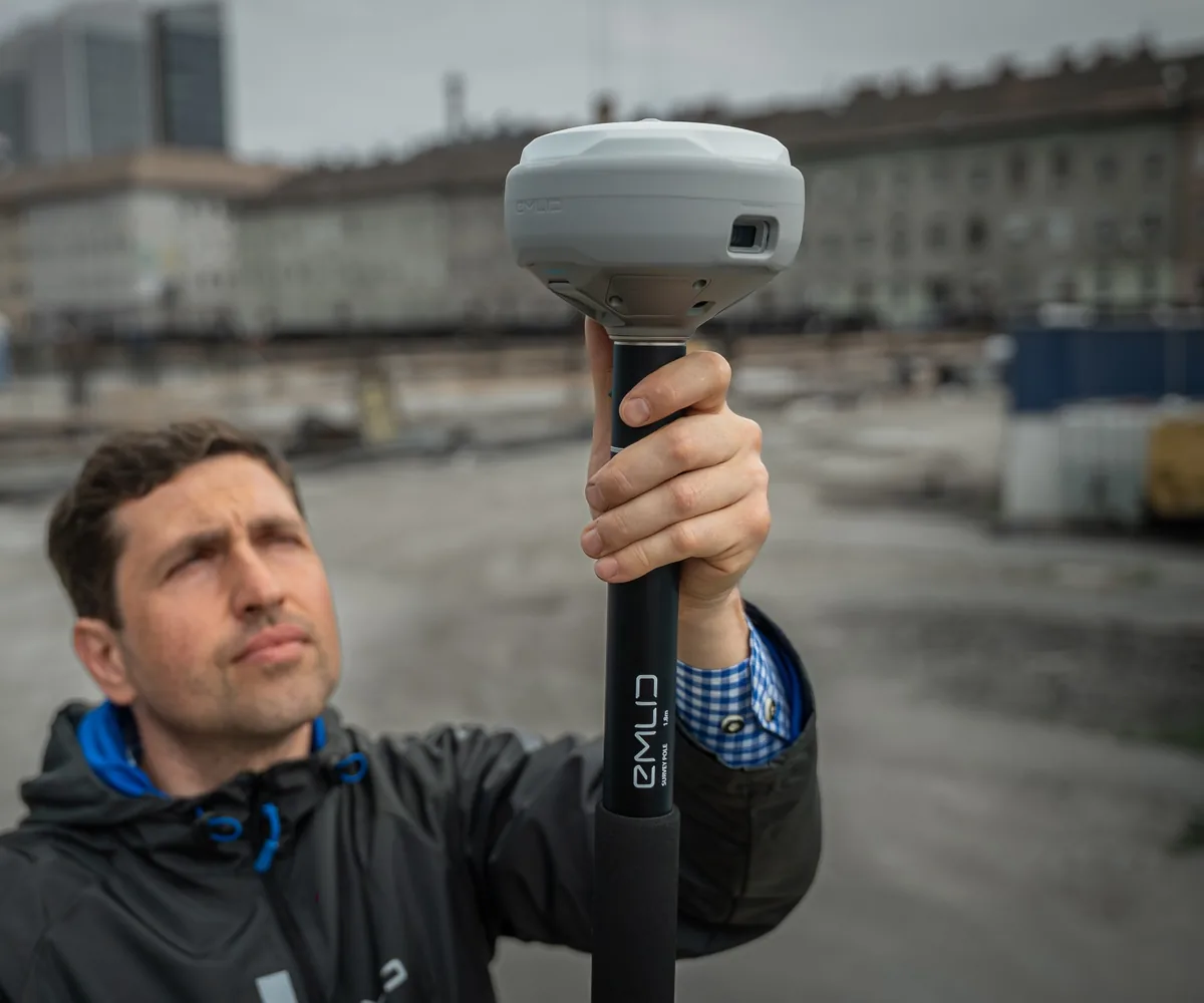 Vermesser mit Emlid Reach RS4 Pro RTK-GNSS-Empfänger auf einer Baustelle